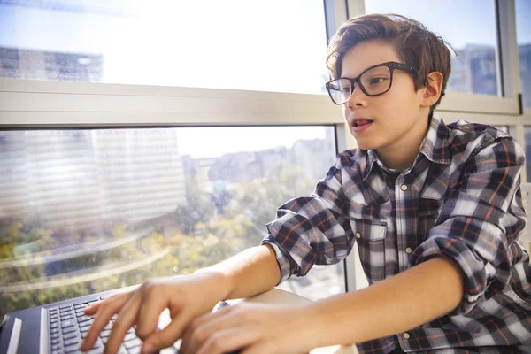 Adolescente menino usando laptop por janela — Fotografia de Stock