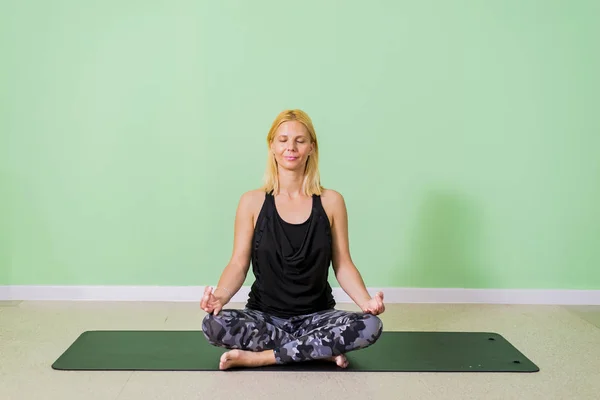 Frau sitzt und praktiziert Yoga im Studio — Stockfoto
