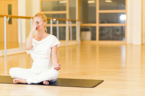 Frau sitzt und praktiziert Yoga im Studio — Stockfoto