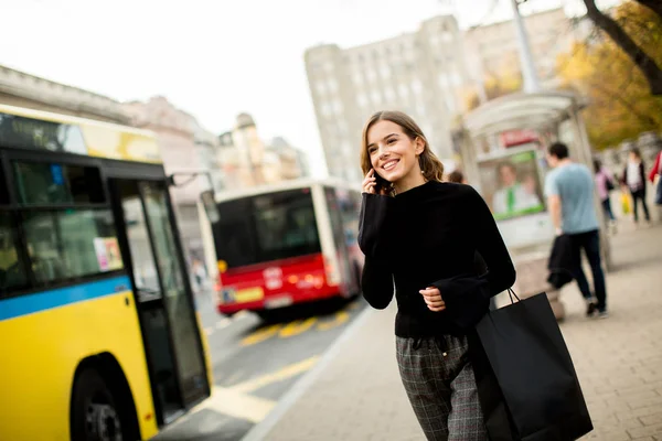 Jonge vrouw te wachten voor de taxi of bus op straat — Stockfoto