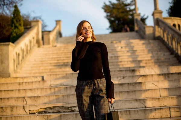 Giovane donna con shopping bag tramite cellulare — Foto Stock