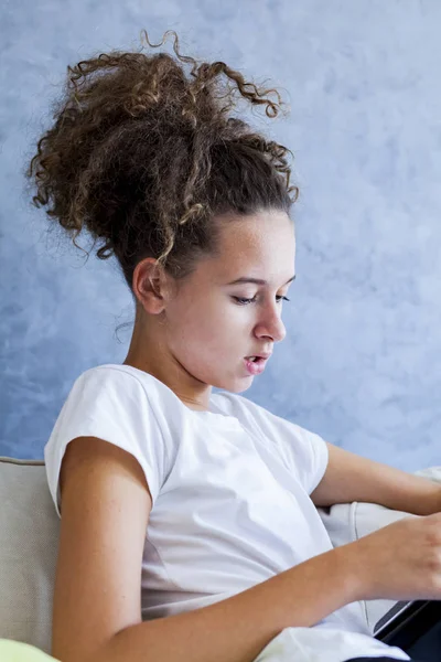 Кучеряве волосся дівчина використовує цифровий планшет на дивані — стокове фото