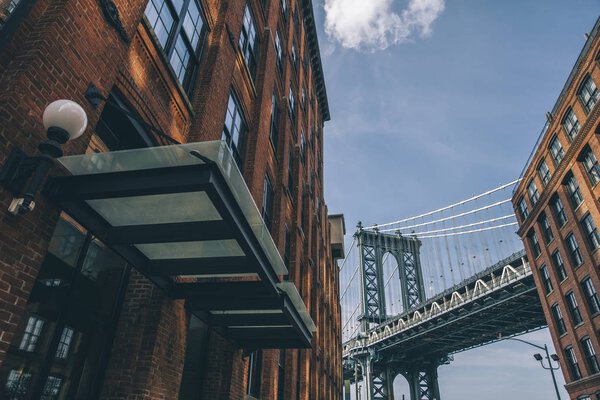 Manhattan bridge seen from a red brick buildings in Brooklyn street in perspective, New York, USA