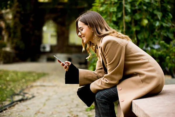 坐在户外和使用手机的年轻妇女 — 图库照片