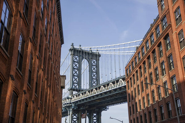 Manhattan bridge seen from a red brick buildings in Brooklyn street in perspective, New York, USA