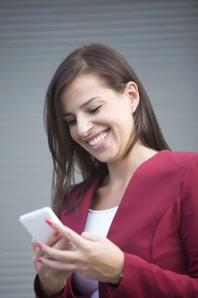 年轻女实业家在红色夹克使用手机 — 图库照片