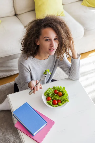 Bovenaanzicht op tiener meisje krullend haar eten Salade — Stockfoto