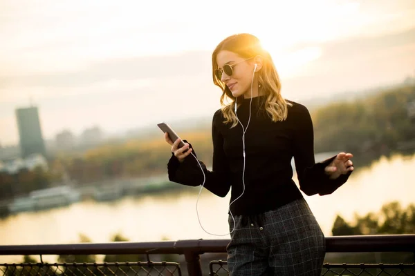 Mujer de moda escuchando música desde el teléfono inteligente — Foto de Stock