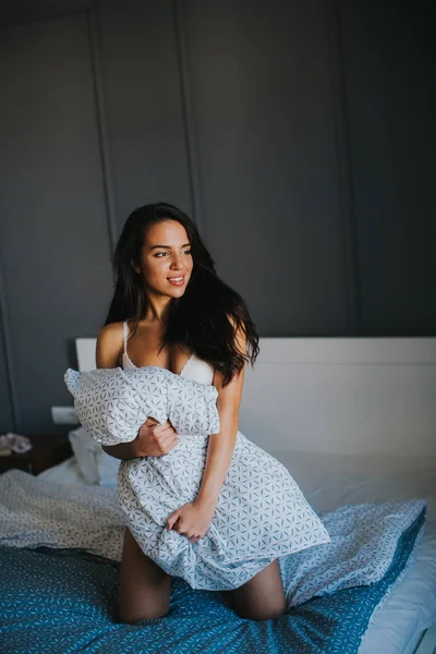 Mladá žena s polštářem na posteli — Stock fotografie