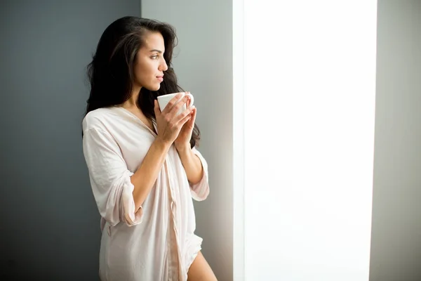 Mujer joven con taza en el dormitorio —  Fotos de Stock