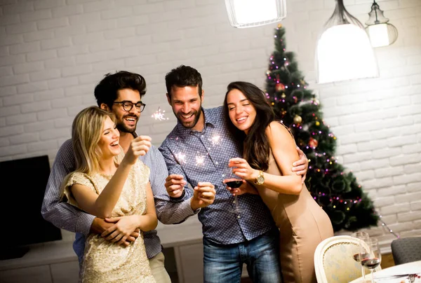 Alegres mujeres y hombres celebrando la víspera de Año Nuevo con destellos y —  Fotos de Stock