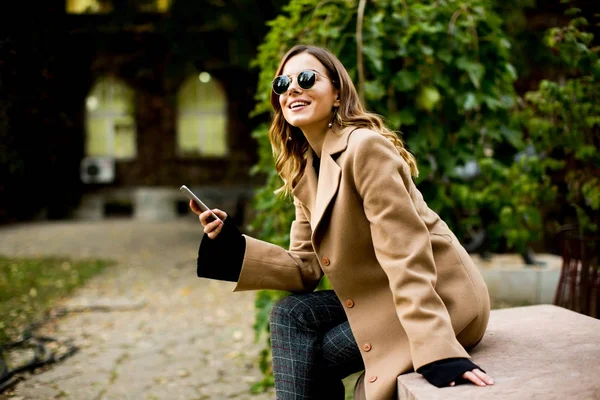 Mujer moderna usando el teléfono móvil en otoño al aire libre —  Fotos de Stock