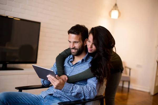 Young couple sitting in the living room and using tablet — Stock Photo, Image