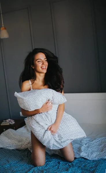 Giovane donna con cuscino sul letto — Foto Stock