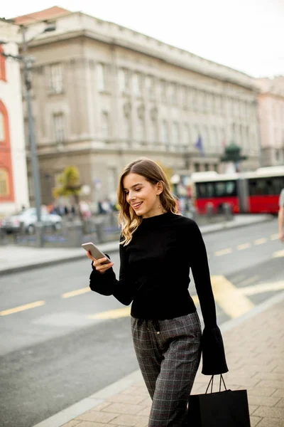 Mujer joven en la calle con teléfono móvil — Foto de Stock
