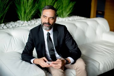 Yakışıklı işadamı cep telefonundan yazarak.