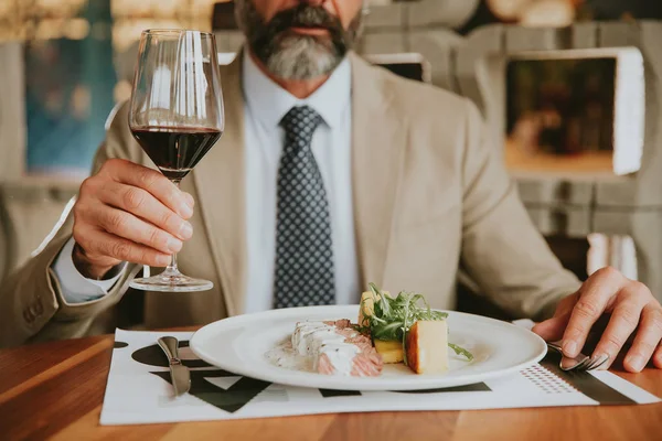 Bello uomo d'affari barbuto che pranza e beve vino rosso — Foto Stock