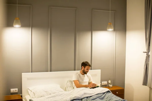 Jovem homem lendo livro na cama — Fotografia de Stock