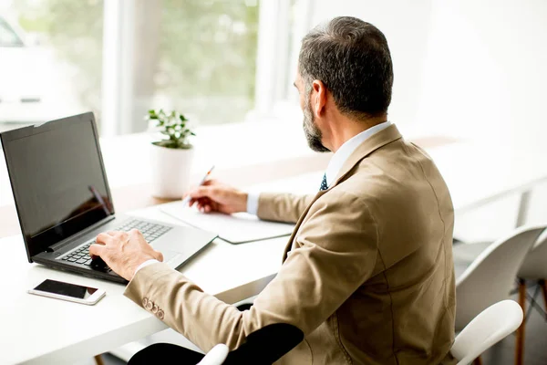 Bonito empresário de meia-idade trabalhando no laptop no escritório — Fotografia de Stock