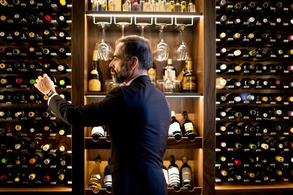Άνθρωπος επιλέγει ένα μπουκάλι κρασί — Φωτογραφία Αρχείου