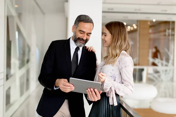 Middelbare leeftijd zakenman en jonge zakenvrouw met tablet — Stockfoto