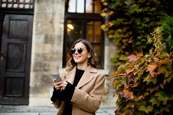 Mujer moderna usando el teléfono móvil en otoño al aire libre —  Fotos de Stock