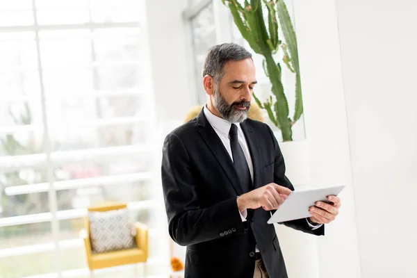 Geschäftsmann mittleren Alters mit Tablet im Büro — Stockfoto