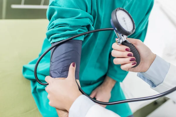 Médico feminino verificando a pressão arterial de um paciente — Fotografia de Stock