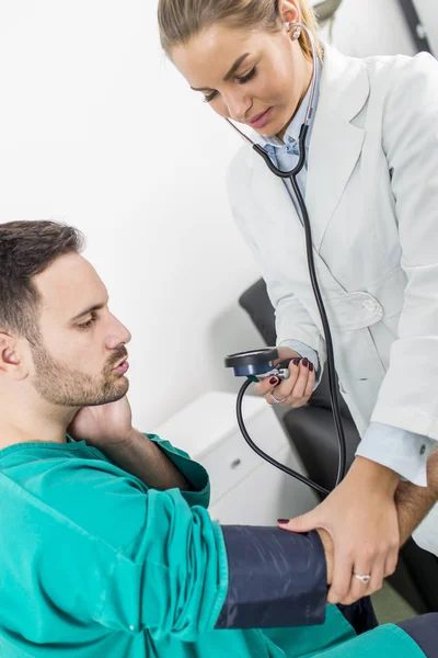 Médico feminino verificando a pressão arterial de um paciente — Fotografia de Stock