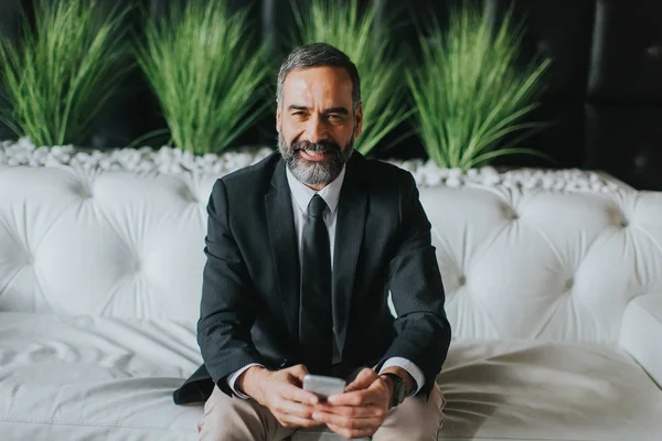 Orta yaşlı işadamı cep telefonuyla s üzerinde modern ofis