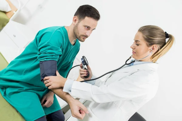 Médico feminino verificando a pressão arterial de um paciente — Fotografia de Stock