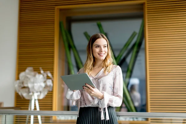 Jeune femme d'affaires debout avec tablette numérique au bureau — Photo