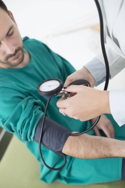 Kadın doktor, hastanın kan basıncını ölçüyor.