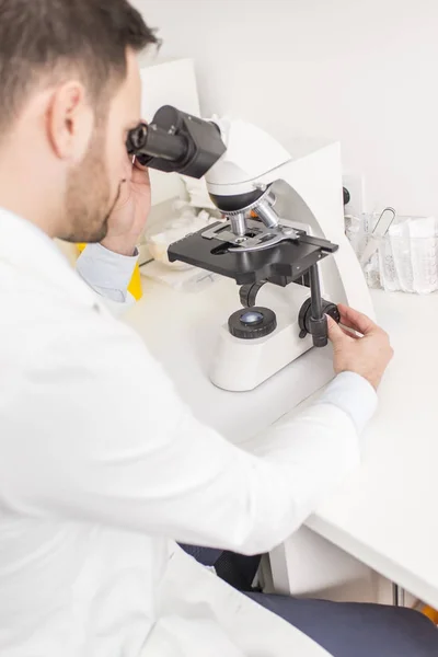 El doctor mira a través del microscopio. — Foto de Stock