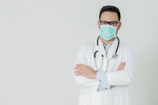Knappe jonge dokter in witte medische uniform en masker is looki — Stockfoto