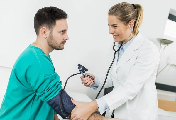 Kobieta lekarz sprawdzający ciśnienie krwi pacjenta — Zdjęcie stockowe
