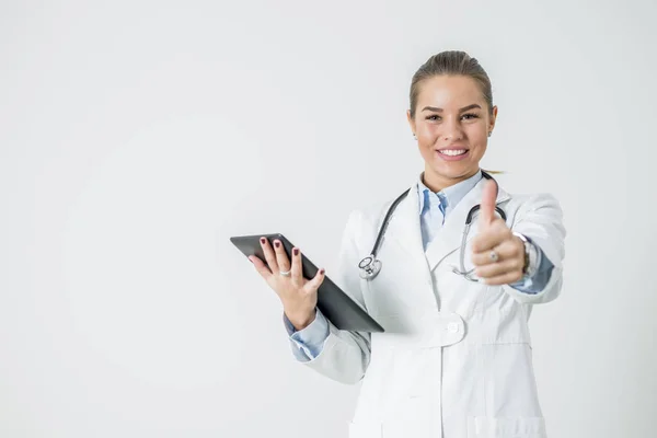 Jovem médica com comprimido mostrando o polegar para cima — Fotografia de Stock