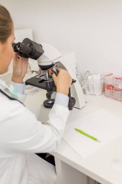 Bir labo içinde mikroskop arayan kadın bilim öğrenci odaklı