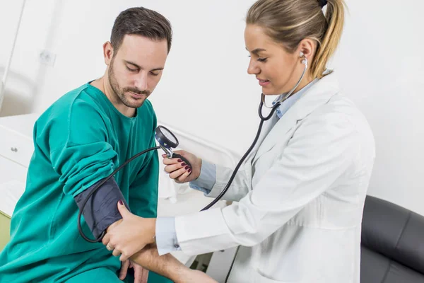Kvinnlig läkare kontrollerar blodtrycket hos en patient — Stockfoto