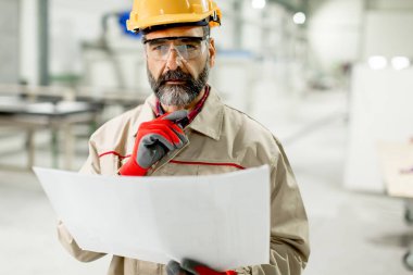 Fabrika planında bakarak yakışıklı olgun mühendisi
