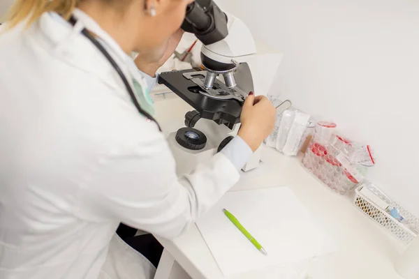 Vrouwelijke wetenschap student op zoek in een microscoop gericht — Stockfoto