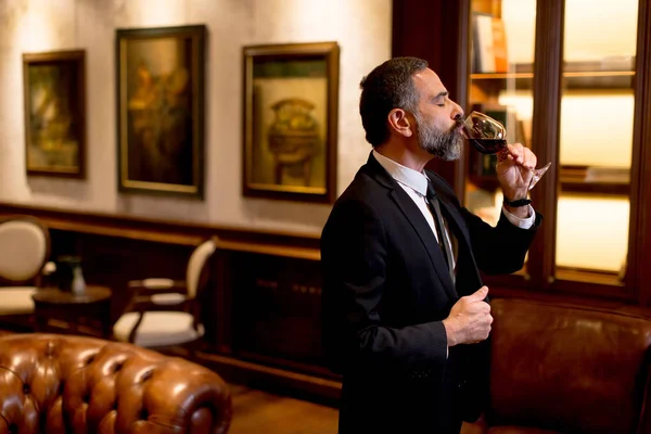 Handsome elegant businessman drinking red wine in bar — Stock Photo, Image