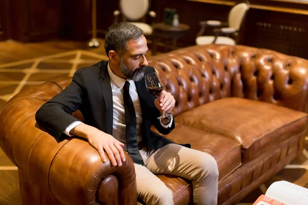 Handsome elegant businessman drinking red wine in bar — Stock Photo, Image