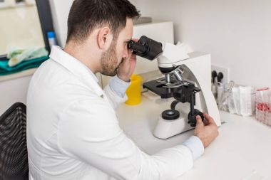 Laboratuvarda mikroskoba bakan bir bilim adamı