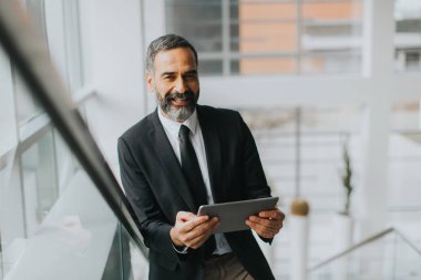 Yakışıklı orta yaş işadamı saatlerin Office dijital tablet ile