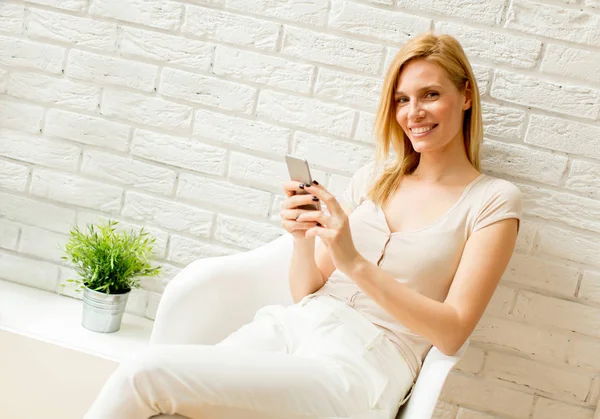 Kobieta blonde przy użyciu telefonu komórkowego w pokoju — Zdjęcie stockowe