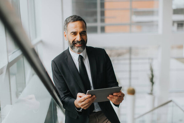 Красивый бизнесмен среднего возраста с цифровым планшетом в офисе
