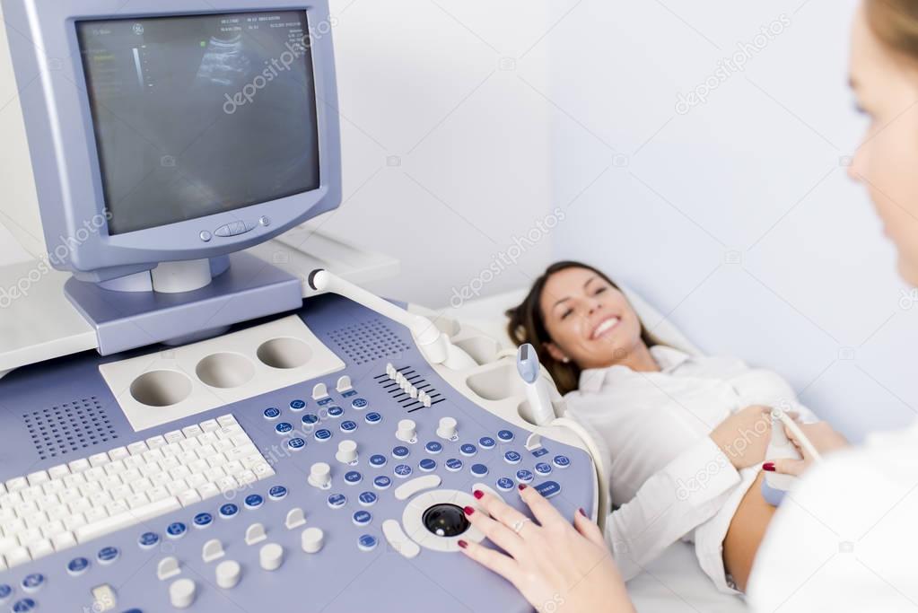 Pregnant young woman at gynecologist having her baby examined with ultrasound device