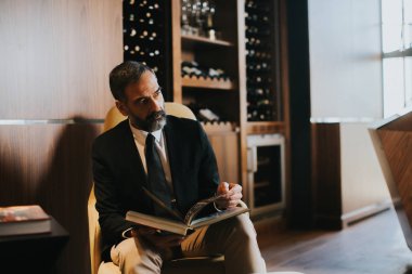 Yakışıklı orta yaşlı işadamı kanepede kitap okuma