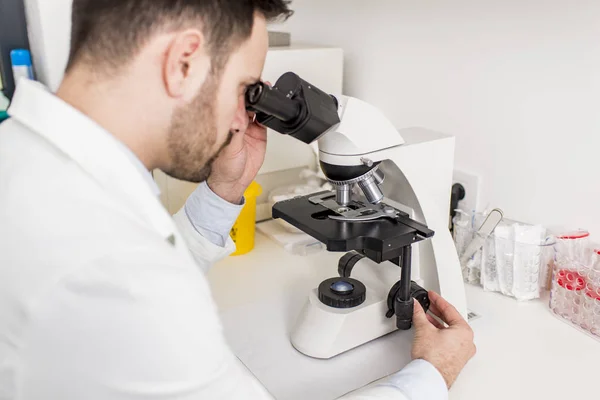 Ученый смотрит в микроскоп в лаборатории — стоковое фото